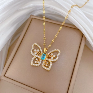 Detail of gold butterfly necklace with blue gemstone and diamonds in a jewelry box