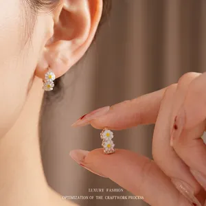 Vintage gold daisy enamel hoop earrings featuring white petals for a luxury retro look