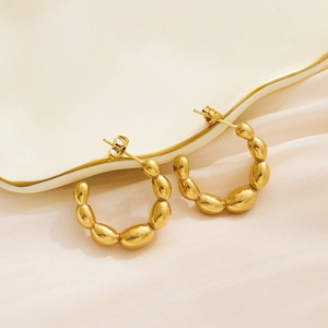 Macro view of gold-plated hoop earrings featuring a unique irregular beaded texture