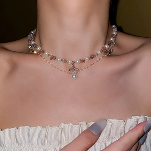 Close-up of double layer necklace with pearls pink crystals and a rhinestone cross pendant