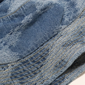 Close-up of blue washed denim bucket hat showing fabric texture and yellow stitching