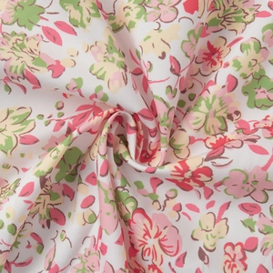 Close-up detail of soft white floral cotton fabric with pink and yellow flower patterns