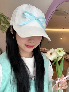 Detail of white baseball cap featuring a light blue silk bow and clean texture