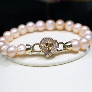 Pink freshwater pearl bracelet with camellia diamond clasp shown on elegant stand
