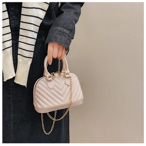 Detail of a beige mini shell jelly bag with gold chain strap and V-quilted texture