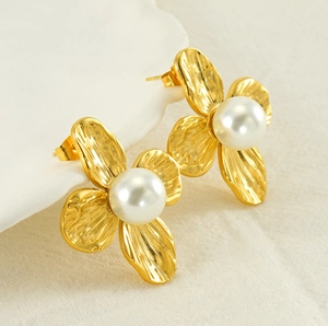 Close-up of vintage golden hammered metal flower earrings with a large white center pearl