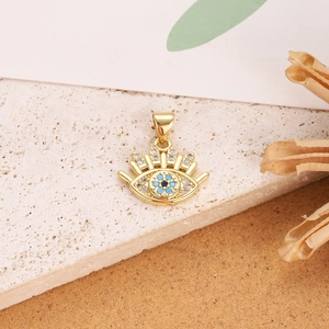 Detailed close-up of a gold-plated evil eye pendant with blue enamel and clear crystals