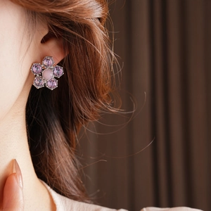 Détail macro de boucles d'oreilles vintage avec pétales violets portées par un mannequin