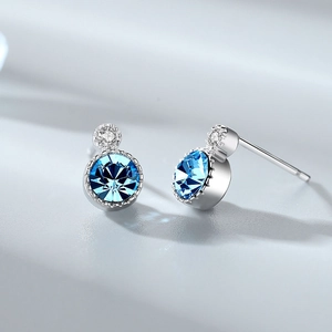 Macro shot of silver stud earrings with round blue gemstones and small side stones