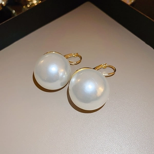 Gros plan d'élégantes perles blanches sur crochets dorés avec un coffret cadeau chic