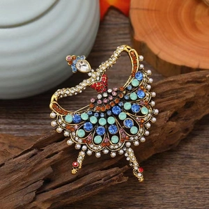 Vintage ballerina brooch with blue rhinestones and pearls on a natural wood surface