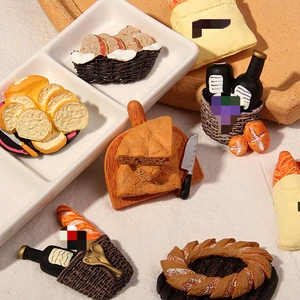 Flat lay of miniature resin food models including bread slices, wine bottles, and cheese board