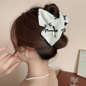 Detail of fabric bow hair claw clip in black and white pattern on back of head