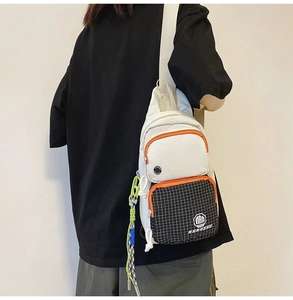 Close-up of white canvas chest bag with orange zipper and checkered pocket detail