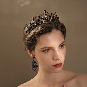 Close-up of elegant black crystal bridal crown and geometric drop earrings on model