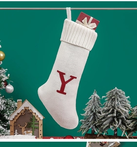 Detail of white knitted Christmas stocking with red letter Y among festive decorations