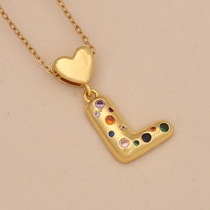 Macro shot of a golden heart pendant with colorful zircon stones and letter L detail