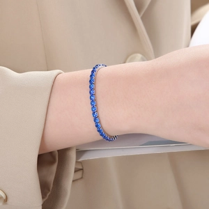 Close-up of blue zircon tennis bracelet on model's wrist with elegant silver setting