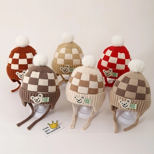 Detail van gebreide kindermutsen met kleurrijke schaakbordpatronen en zachte pompons