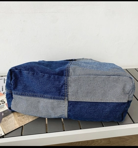 Detail of patchwork denim tote with contrast stitching and textured canvas fabric