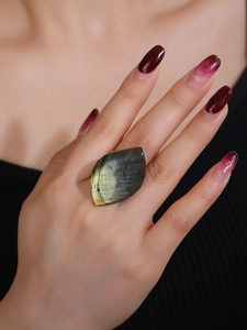 Close-up of a leaf-shaped labradorite ring with natural blue-green flash on female finger