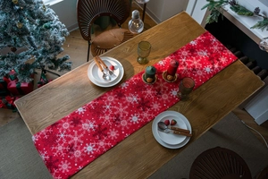 Detail view of red Christmas table runner with white snowflake patterns in cozy dining setting