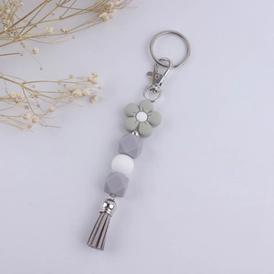 Detail of grey silicone floral keychain with beaded strap and leather tassel accent