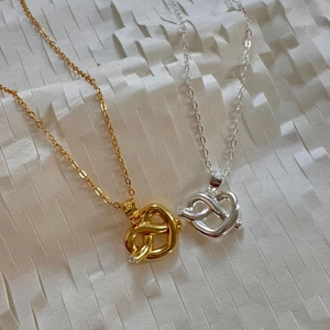 Macro detail of S925 sterling silver heart knot pendants in gold and silver finish