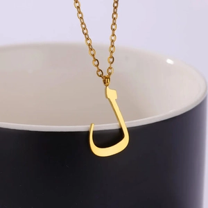 Detail of a golden Arabic letter pendant hanging on a minimalist ceramic cup edge
