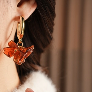 Macro side view of amber resin flower petal earring worn on model for retro fashion