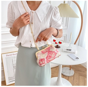 Fashion model showcasing a pink floral embroidered qipao handbag with gold chain strap