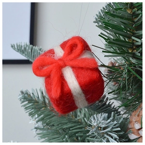 Detail of wool felt red gift box ornament hanging on a Christmas tree branch