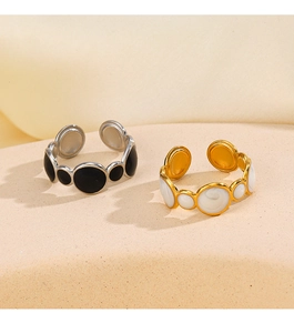Detail view of gold and silver plated geometric drip oil rings on a warm beige stand