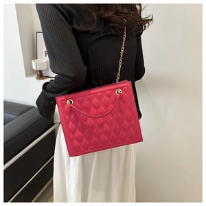 Detail of rose pink quilted crossbody bag with gold chain strap on a stylish model