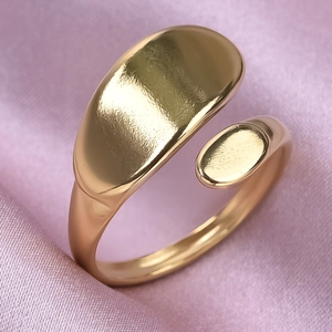 Close-up of gold curved line ring with pebble design on soft pink silk fabric