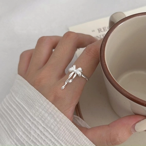 Detail of 925 sterling silver bow knot ring worn on hand with a lifestyle backdrop