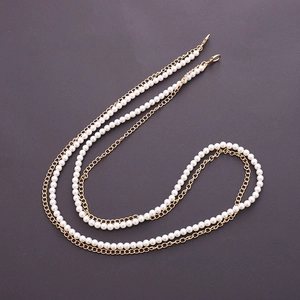 Detail of elegant white double pearl and gold chain strap with metallic lobster clasps