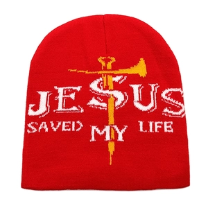 Dettaglio del berretto rosso con testo Jesus Saved My Life bianco e croce gialla