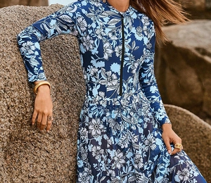 Detailed close-up of floral print surf swimsuit with front zipper on rocky background