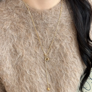Close-up of golden sun pendant with amber stone on a long Y-shaped snake chain
