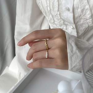 Detail of minimalist gold bead ring and delicate pearl ring set on model hand