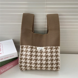 Close-up of houndstooth knit tote bag with brand label and textured fabric detail
