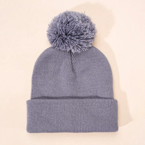 Close-up of purple knitted beanie with a matching pompom showing soft wool textures