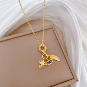 Gold stainless steel necklace with leaf and evil eye pendants on a soft jewelry box