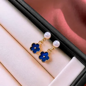 Elegant blue enamel flower earrings with pearls on a luxury white jewelry box