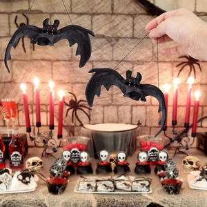 Realistic black rubber Halloween bat hanging decor with red eyes in spooky party scene