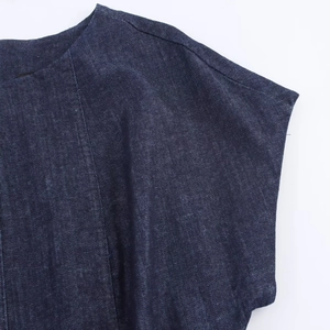 Détail de la couture d'épaule et du poignet sur une robe midi en jean bleu foncé