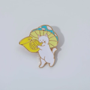 Cute enamel pin featuring a cartoon white cat wearing a mushroom hat playing the French horn