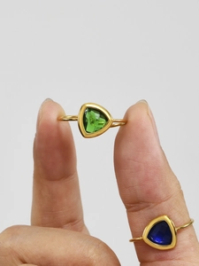 Detail van 18k vergulde driehoekige ringen met blauwe en groene glazen edelstenen