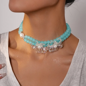 Detail of double-layer beaded necklace with light blue glass beads and floral charms